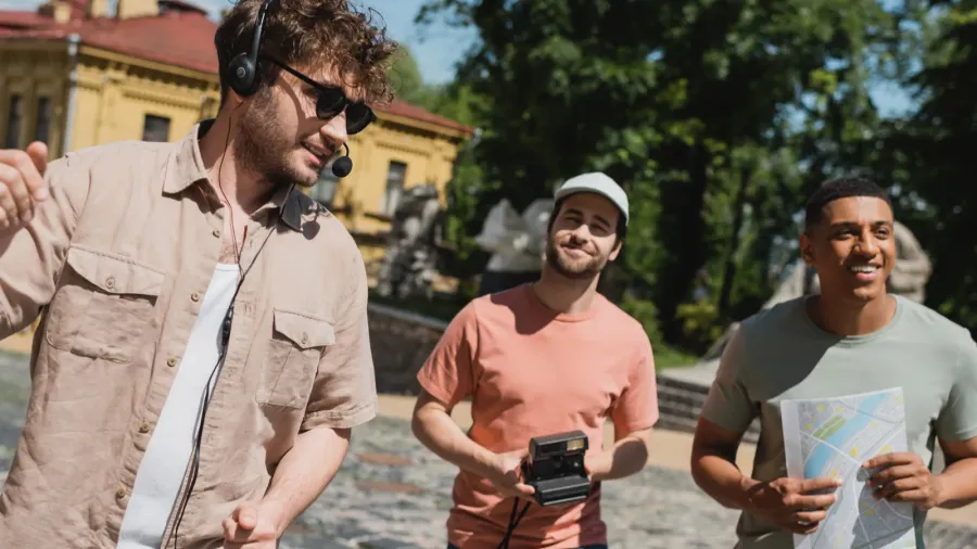 positive guide in sunglasses and headset leading tour for multiethnic