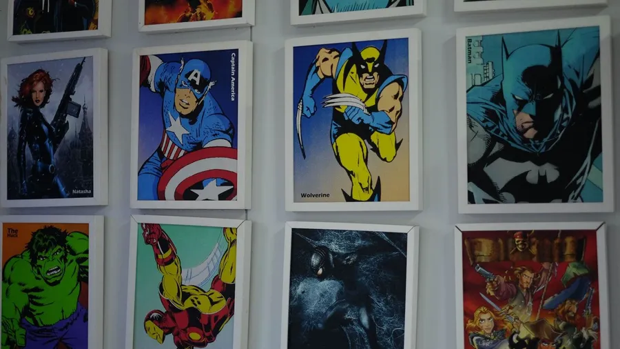 Marvel and DC superhero posters on a white wall.