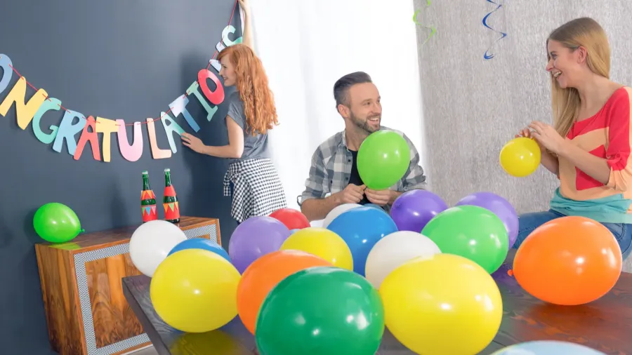 A happy family in a living room making the preparations for a grad party with buntings and balloons.
