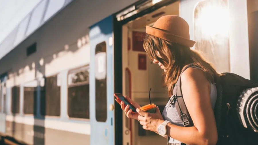 railroad theme beautiful young woman with a backpack uses the