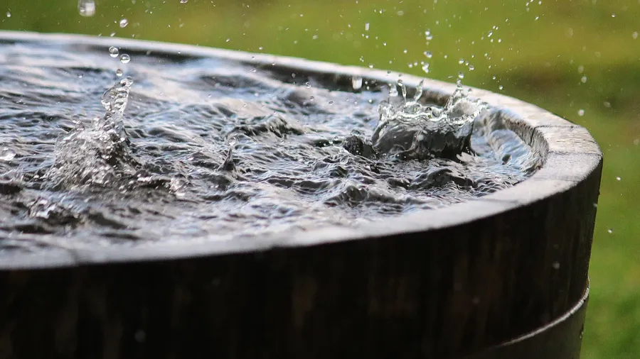 rain is falling in a wooden barrel full of water