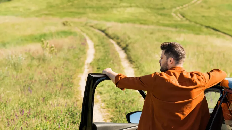rear view of young man standing near his car on