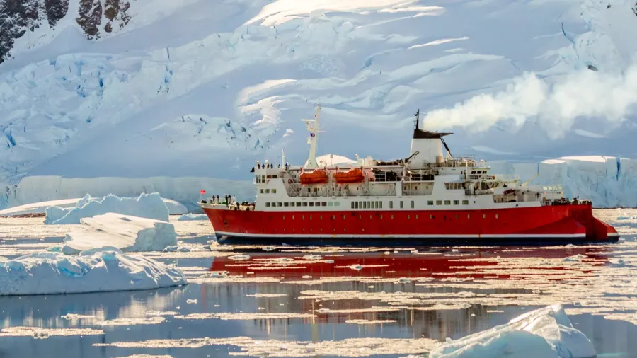 red cruise steamboat drifting among the icebergs with huge rock