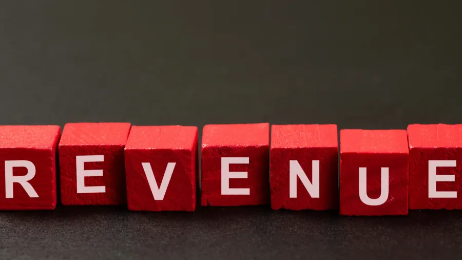 red wooden blocks spelling revenue on a dark background symbolizing