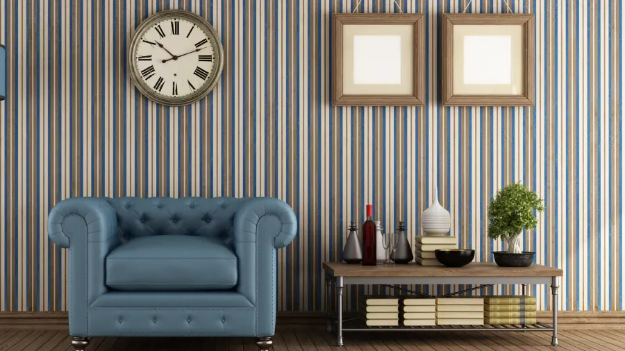 A stylish living room interior with a cozy sofa, wooden table with books, plant, and decor accents with a clock and wooden frames hanging on a colorful striped wallpaper.