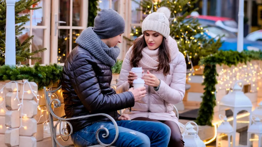romantic couple wearing warm clothes sitting on a bench in