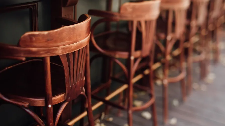 Wooden rustic bar stools on a wooden floor in front of an island.