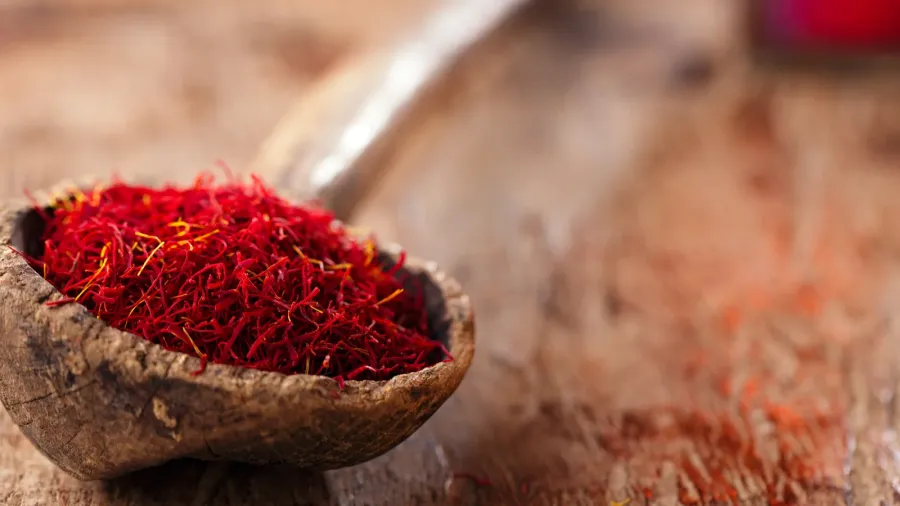 saffron spice in antique wooden spoon on old wood background