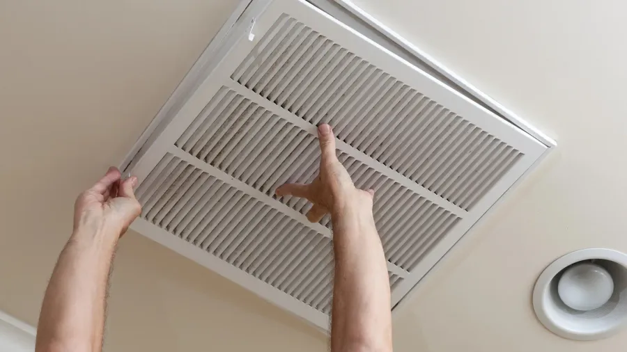 senior man opening air conditioning filter in ceiling