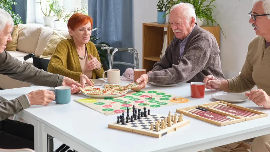 A game zone with people playing board games placed on white table.