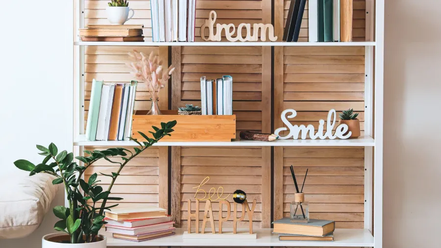 A white shelf with books, reed diffuser, and decor accents.