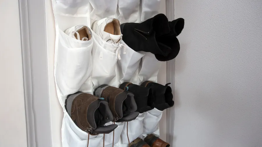 A hanging shoe rack organizer with shoes in it, hanging on a white door.