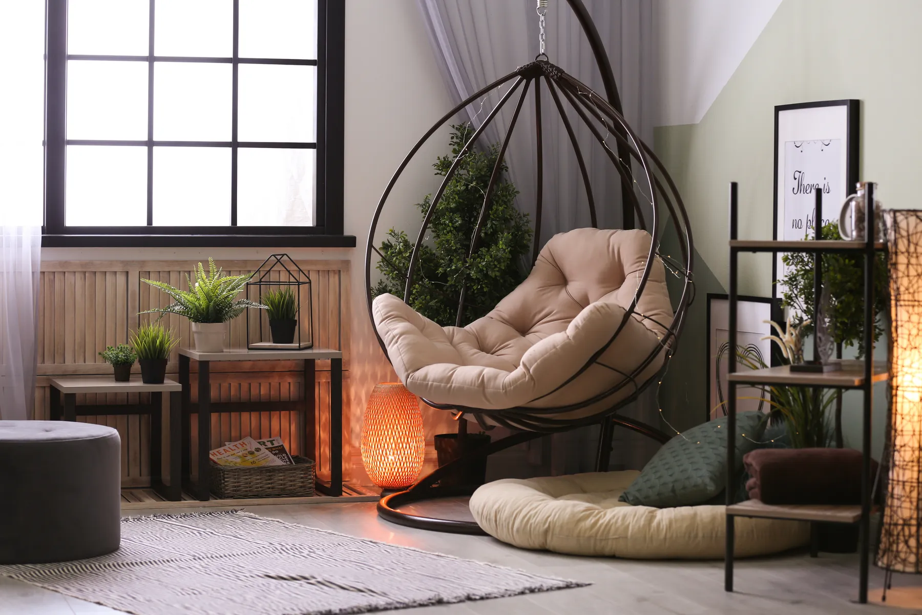 Cozy corner with a hanging chair, small side tables, and potted plants in a bright, relaxing space.