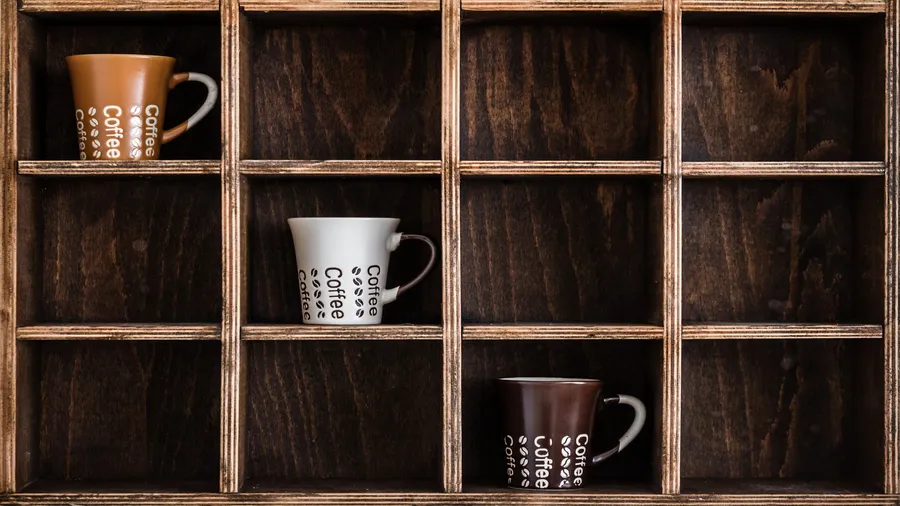 A reclaimed wood shelf with coffee mugs in it.