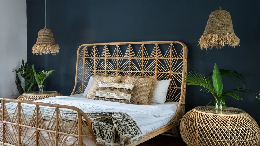 A bedroom interior with bamboo bed, nightstands, plants, and ceiling lamps.