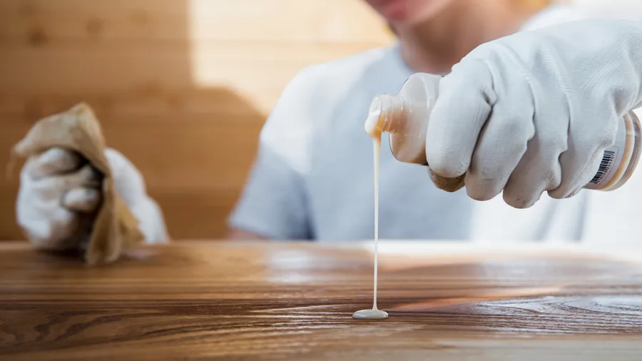 A girl wearing gloves applying wood conditioner on a furniture.