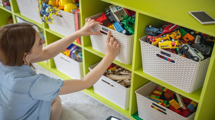 A woman labeling baskets containing toys.