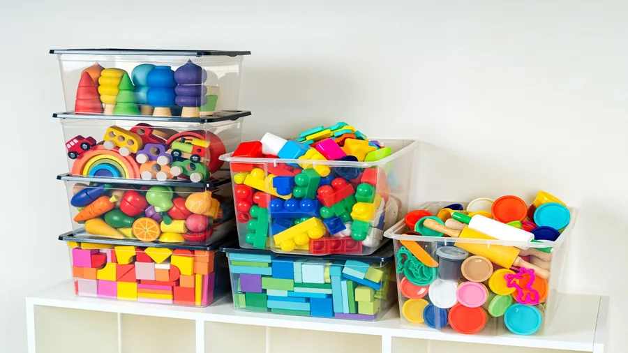 Clear storage containers with different toys stacked on top of each other.