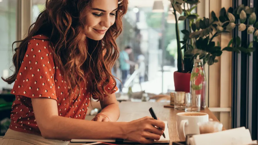 side view of young blogger making notes in notebook at