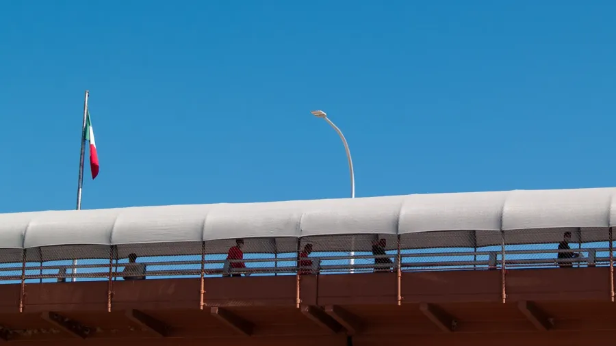 silhouettes of migrants crossing an international bridge into the usmexico