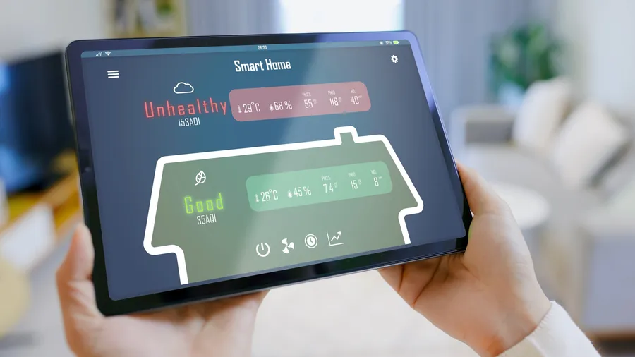 A person holding a smart device displaying air quality in the home and outside.