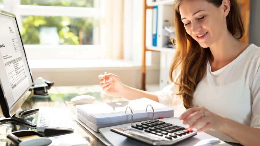 smiling businesswomans hand calculating bill in office