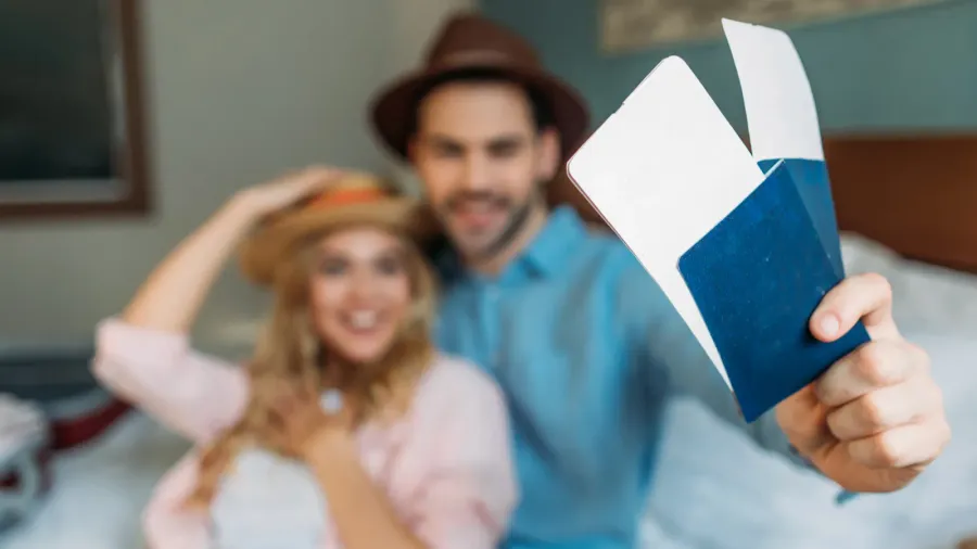 smiling couple in hotel room with passports with tickets on