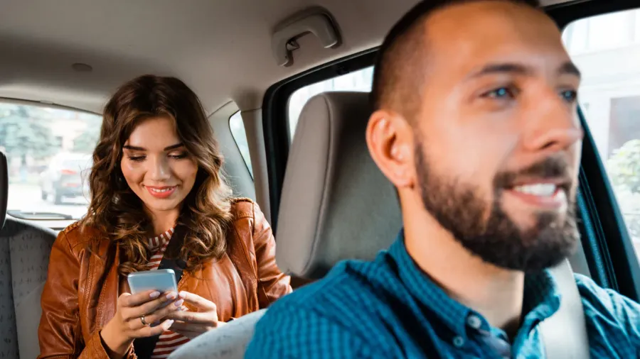 smiling driver talking with female passenger woman using mobile phone