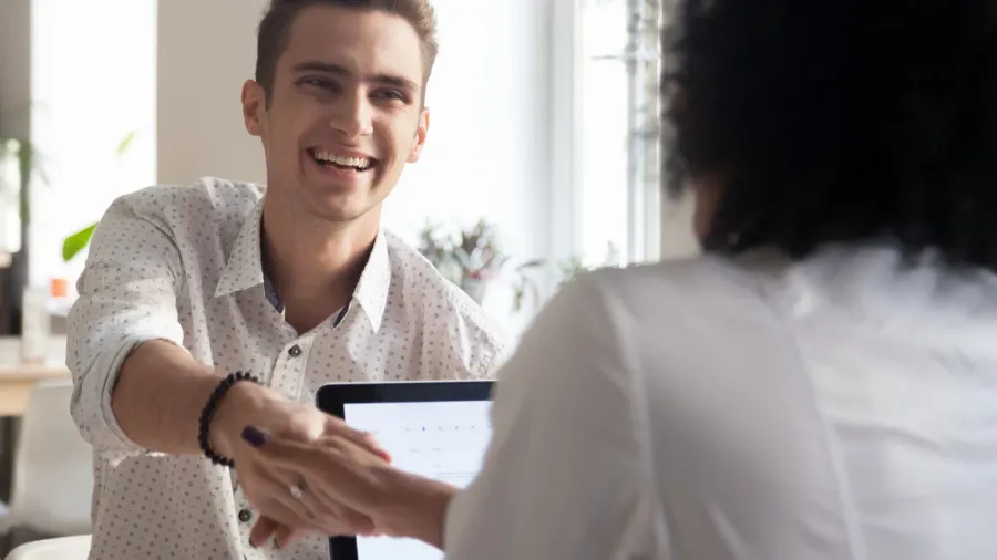 smiling millennial man handshaking african female coworker celeb