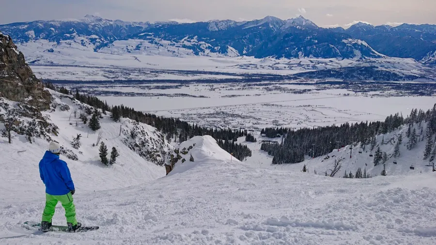 snowboarder observes the snowy landscape before riding down a ski