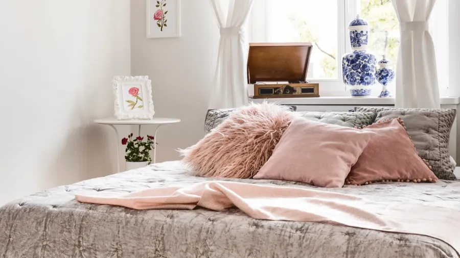 A stylish and inviting bedroom area showcasing decorative pillows, tranquil colors, and natural light filtering through the window.