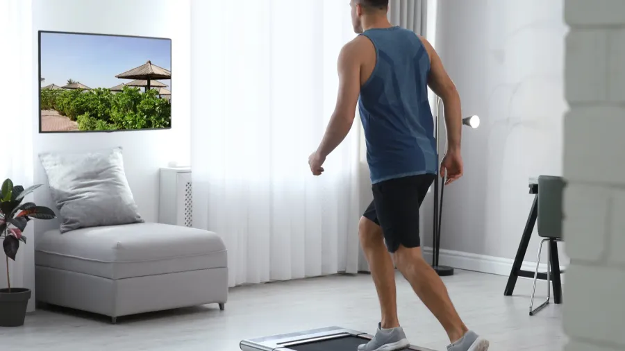 sporty man training on walking treadmill and watching tv at
