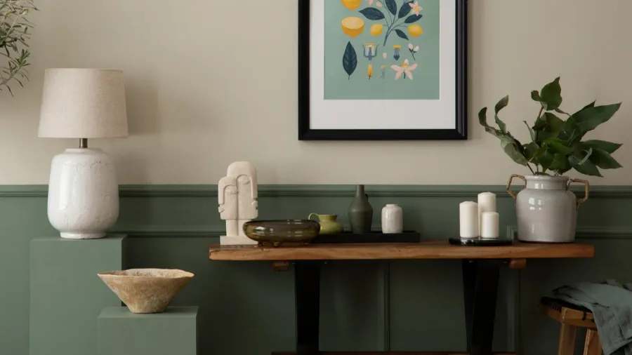 A stylish tabletop display with decorative items, plants, and a lamp against a muted background.