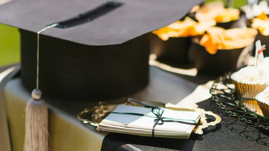 A graduation party table setting with graduation cap and cards placed on a table alongside food.
