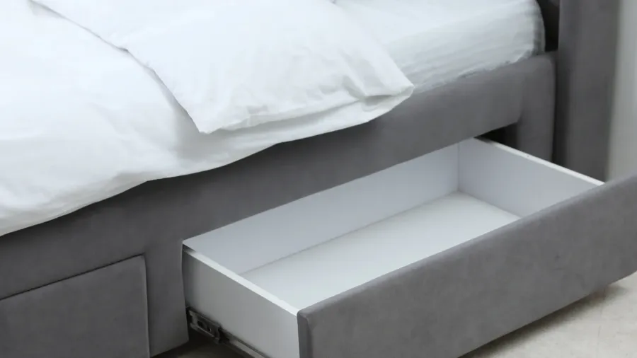 A gray bed with under-bed storage for bedding and essentials.