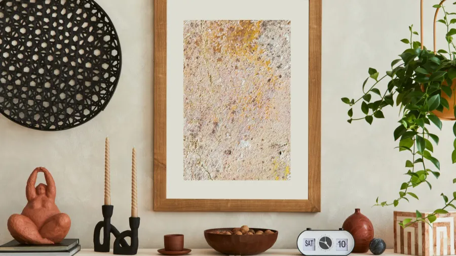 A console table with sculpted decor accents, decorative bowl, and an abstract print in a wooden frame on the wall.