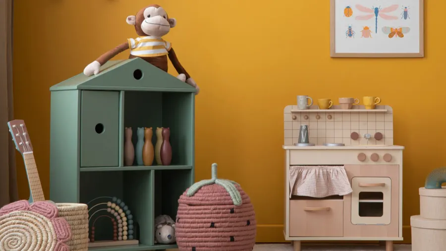 A cute dollhouse with stuffed animals and small play kitchen set in a child's room.