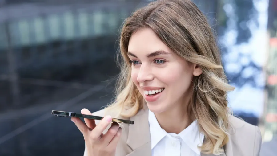 stylish corporate woman records voice message on smartphone talks into