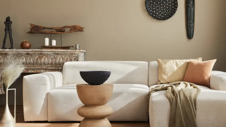 A stylish ethnic living room interior with modular sofa, carved wood coffee table, vintage console table, and cultural decor accents.