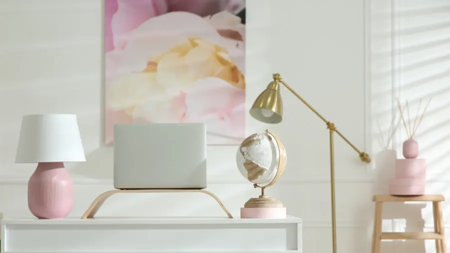 A stylish home office interior with a globe and lamp on the table, a golden floor lamp, and artwork on the wall.