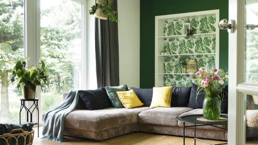 A cozy living room featuring a comfortable sectional sofa adorned with colorful pillows and fresh flowers.
