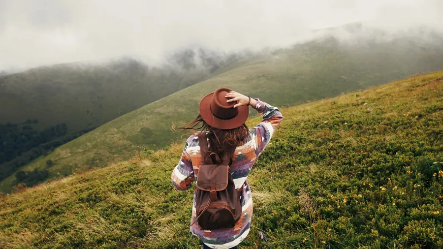 stylish traveler girl in hat with backpack looking at sunny