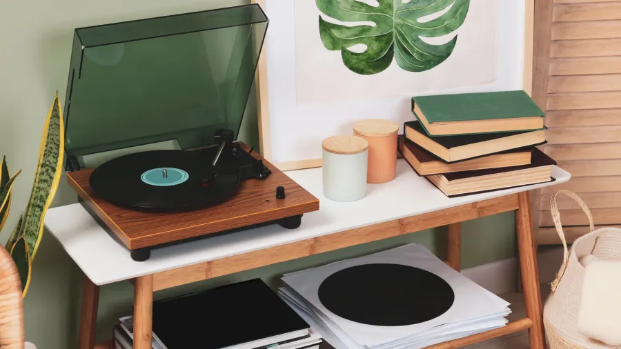 A vintage-style record player on a wooden table with some plants nearby for a retro vibe.