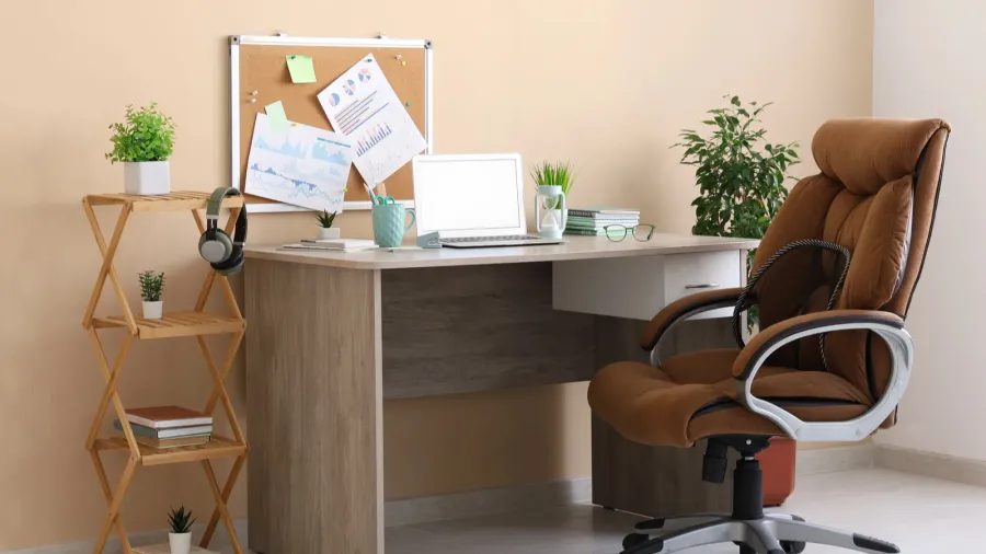 stylish workplace with modern laptop stationery and armchair near beige