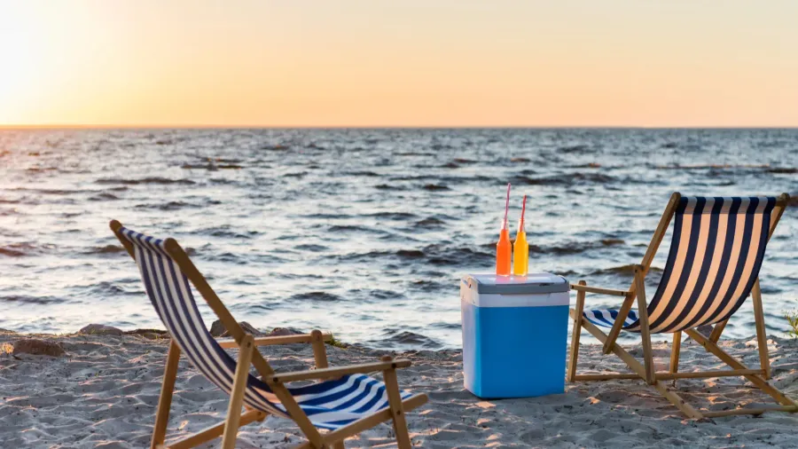 summer drinks on cooler and chaise lounges on sandy beach
