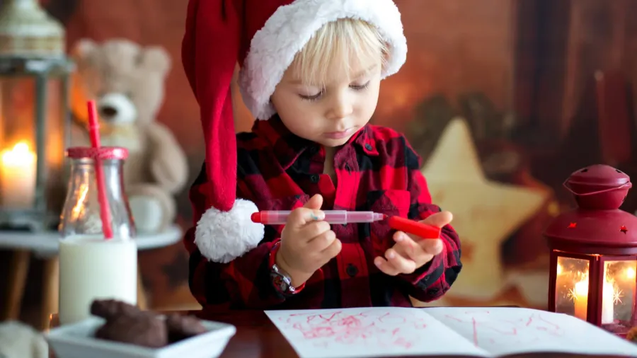 sweet blonde toddler boy writing letter to santa wishing prese