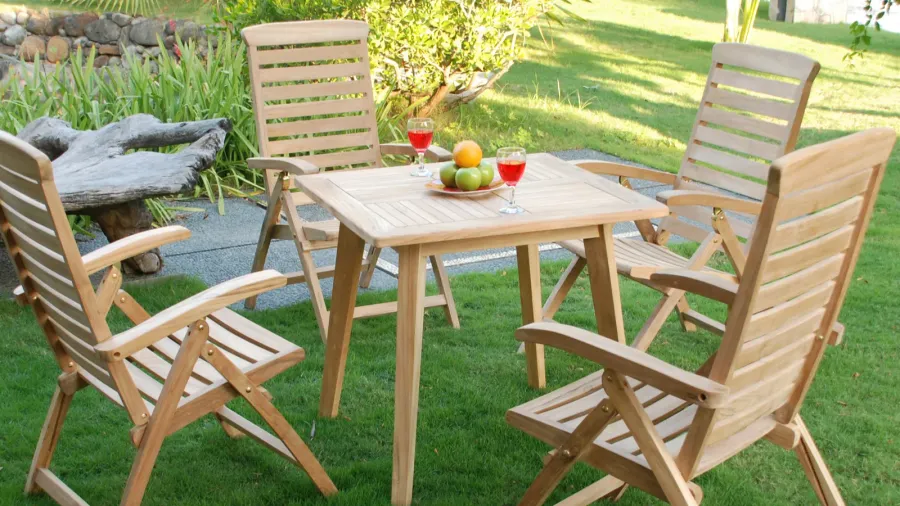 A teak wood dining set with table and chairs on a patio.