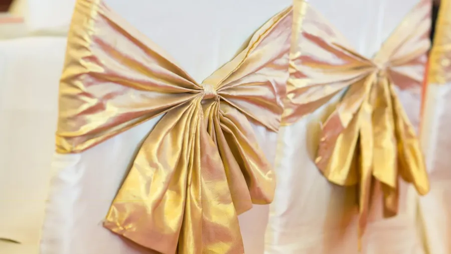 White chairs wrapped with golden ribbons.