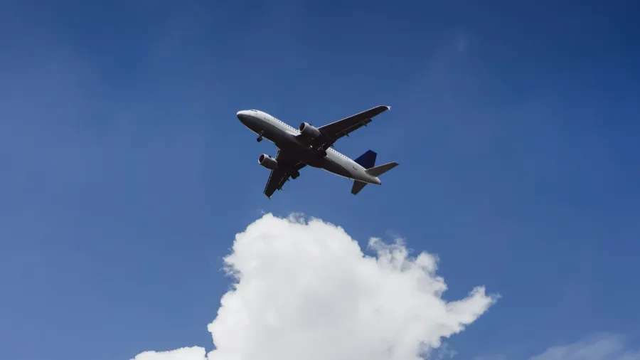 the plane is flying in the blue sky