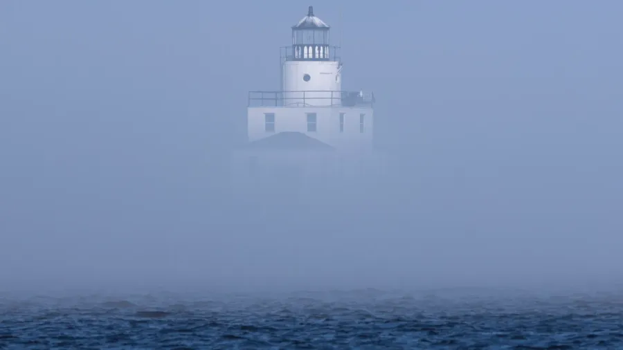 the thick fog partially obscures the lighthouse on lake michigan